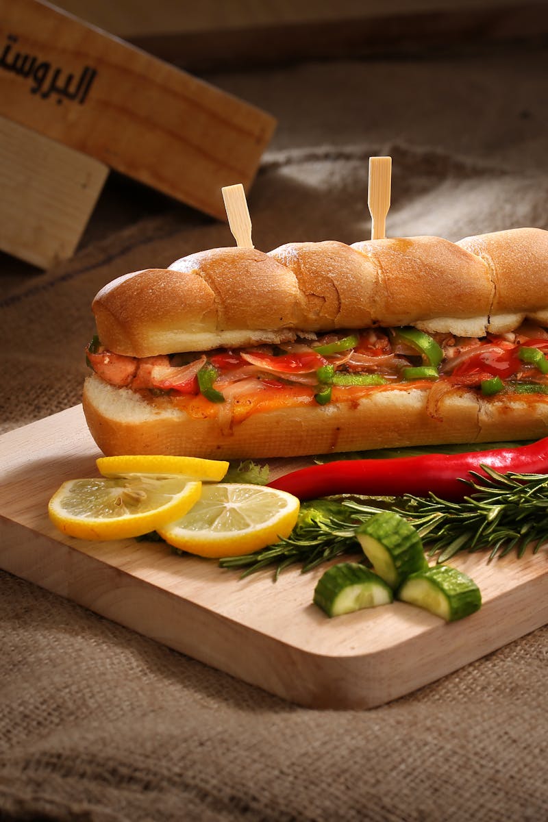 Mouth-watering sandwich with vegetables and sausage on wooden board, perfect for a delicious meal.